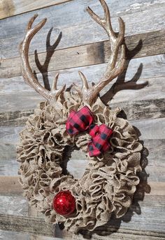 a burlock wreath with red and black plaid bows hanging on a wooden wall