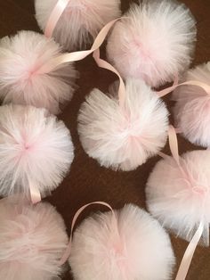 six white pom - poms with pink ribbons on them sitting on a table