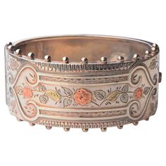 Antique British Sterling Silver Bangle Bracelet in Neoclassical design. Decorated with raised floral ornamentation accented in 14K Rose and Yellow Gold over Silver.V- lock and box clasp. I have one French bangle of very similar design listed in my inventory. British Hallmarked. Maker : J.Bs, Birminghem, year 1883 The band is 26 mm wide; 59 mm x 49mm / size M,S / fits Ø 16-17 cm wrist. Fine used condition. Natural patina on Silver. Slight wear on gilt surfaces, small scratches, and minor dents. S Antique Rose Gold Bracelets For Formal Occasions, Luxury Engraved Ornate Bangle, Etched Rose Gold Jewelry For Formal Occasions, Luxury Antique Engraved Sterling Silver Bracelet, Engraved Rose Gold Bracelet For Wedding, Rose Gold Engraved Gold Bracelet For Wedding, Rose Gold Engraved Bracelet For Wedding, Heirloom Etched Rose Gold Jewelry, Heirloom Style Etched Rose Gold Jewelry