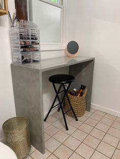 a small desk with two stools next to it and a mirror on the wall