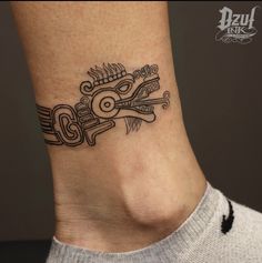 a black and white tattoo design on the side of a woman's ankle,