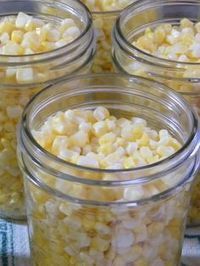 several jars filled with corn sitting on top of a table