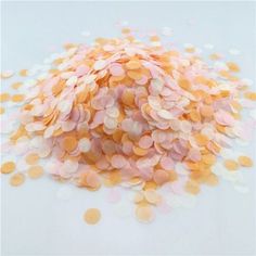 pink and orange confetti sprinkles are scattered on a white surface