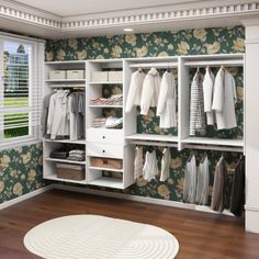 a walk in closet filled with clothes next to a white rug on top of a hard wood floor