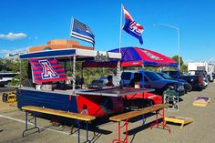 an outdoor food cart with flags on the roof and picnic tables in the parking lot