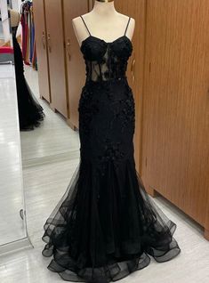 Full of allure and grace, this prom dress captivates with its exquisite detailing and flawless design. The gown features a bodice rich in floral appliques that trail down a figure-hugging silhouette, culminating in a flared tulle skirt that floats with every step. Its transparent midsection adds a touch of intrigue, balanced by the classic elegance of the black fabric. With a blend of traditional beauty and contemporary chic, this dress is an embodiment of the poise and mystery fitting for a night of celebration and sophistication. Black Prom Dress With Butterflies, Black Prom Dresses With Corset, Vintage Corset Prom Dress, Laced Black Prom Dress, Black Lace Prom Dresses, Black A Line Prom Dress, Black Prom Dress With Corset, Black Prom Dress Elegant, Masquerade Dress Ideas Prom