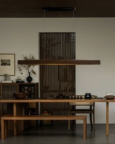 a wooden table sitting next to a shelf filled with vases and other items on top of it