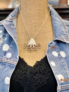 an octopus necklace is displayed on a mannequin's torso, wearing a denim jacket