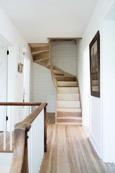 a wooden staircase leading up to the second floor in a white house with wood floors