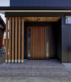 the front entrance to a modern home with wood slats on the side and concrete steps leading up to it