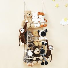 there are many stuffed animals hanging on the wall above this shelving unit that is filled with teddy bears