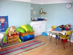 a child's room with blue walls and wooden flooring, toys on the table