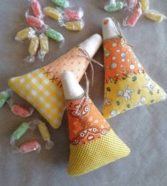 three colorful candy cones are on the ground with candies scattered around them, including one in orange and yellow