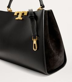 Find TORY BURCH Leather Eleanor Top-handle Bag on Editorialist. The Tory Burch Eleanor bag is crafted from leather and features a top handle, a detachable and adjustable shoulder strap, and a gold-tone logo plaque closure. It can be worn on the shoulder, hand carried, or worn crossbody. The bag has a spacious interior with a suede lining. Tory Burch Eleanor Bag, Harrods Bear, Tory Burch Satchel, Tory Burch Eleanor, Tory Burch Shoulder Bag, Cross Body Satchel, Foodie Gifts, Watch Gifts, Medium Bags