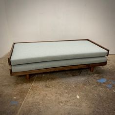 a blue couch sitting on top of a wooden frame in an empty room with no one around