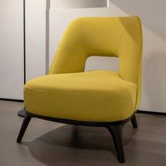 a yellow chair sitting on top of a hard wood floor next to a white wall