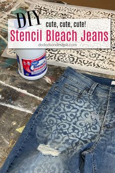 an upcycled pair of jeans with stencil and glue sitting on the floor