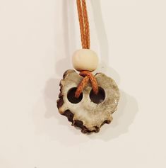 a piece of driftwood with two beads hanging from it's end on a cord