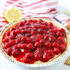 a pie with cherries on it sitting next to sliced lemons and crackers