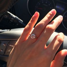 a woman's hand on the steering wheel of a car with a diamond ring