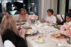 four women sitting at a table with plates of food and flowers in front of them