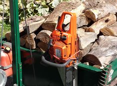 an orange chainsaw sitting on top of a pile of wood