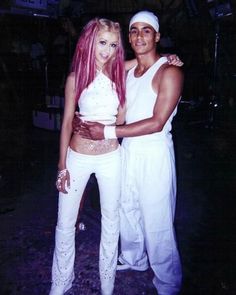 two people standing next to each other wearing white outfits and posing for the camera with their arms around one another