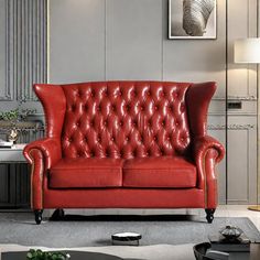 a red leather couch sitting in a living room next to a coffee table and lamp