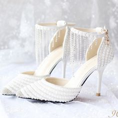 a pair of white high heeled shoes with pearls