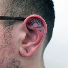 a man with glasses on his head has an ear tattoo