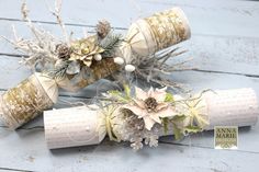 three rolls of twine wrapped in paper and decorated with flowers, pine cones and snowflakes