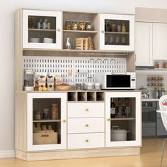 a kitchen with white cabinets and wooden flooring next to a dining room table filled with chairs