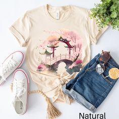 Discover our captivating Cherry Blossom T-shirt, merging Japanese serenity with delicate beauty. This unique piece features a stunning image of a Japanese arched bridge and cherry blossoms. Crafted from premium fabric, it offers comfort and durability. Perfect for nature lovers and travel enthusiasts, let it inspire you to follow your dreams and explore the world. Order your Cherry Blossom T-shirt today and experience the allure of Japan wherever you go. Production Time:  2-5 business days (usua Pink Shirt As Spring Gift, Pink Shirt For Spring Gift, Spring Gift Shirt With Relaxed Fit, Spring Printed Tops For Gift, Printed Tops For Spring, Printed Tops For Spring Gift, Short Sleeve Tops For Spring, Casual Spring Shirt Perfect For Gifts, Graphic Tee Tops For Spring