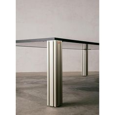 the table is made out of metal and has a glass top with two columns on each side