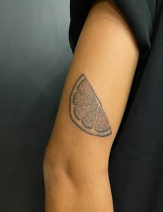 a tattoo on the arm of a person with a slice of orange in its hand