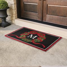 a door mat with a monogrammed christmas wreath on it and the letter m