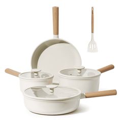 a set of white pots and pans with wooden utensils