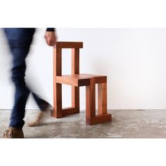 a person walking past a small wooden chair