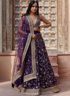 a woman in a purple and gold lehenga