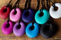 six different colored donuts hanging from black cords on a wooden table with string attached to them