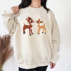 Retro Rudolph And Clarice Sweatshirt, Rudolph Red Nosed Christmas Cute White Christmas Sweater, Cute White Christmas Sweatshirt, Cozy Christmas Tops With Relaxed Fit, Cozy Relaxed Fit Christmas Tops, White Christmas Sweatshirt Relaxed Fit, White Relaxed Fit Christmas Sweater, Casual Cozy Christmas Top, Christmas White Sweatshirt For Loungewear, White Christmas Sweatshirt For Loungewear