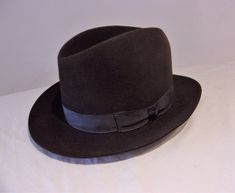 "What a dapper hat this is. An original vintage men's fedora, its classic style makes it difficult to confirm its age, but the label helps put it circa 1940s. In a beautiful cocoa brown, soft felt of lovely quality, it has a tall crown, moderately wide brim with a raw edge finish and a steely grey grosgrain hatband. And in a small size, its just as right for the ladies or young lads, to finish a flawless forties or fifties ensemble to original perfection, starting at the top!  Measurements:  Int Mens Dress Hats, Old Fonts, Tall Crown, Mens Fedora, Top Measurements, Felt Fedora, Cocoa Brown, Mens Dress, Dress Hats