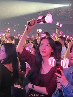 two women holding up hair dryers in front of an audience at a concert with confetti falling from the ceiling