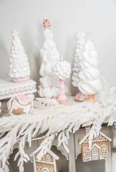 some white and pink christmas decorations on a shelf with gingerbread houses in the background