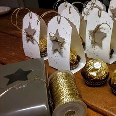 some gold and white cupcakes are sitting on a table with tags attached to them