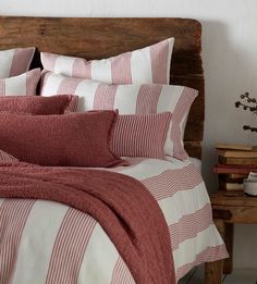 a bed with red and white striped comforter in a room next to a wooden headboard