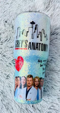 the grey's anatomy tumbler cup is sitting on a white blanket with cityscape in the background