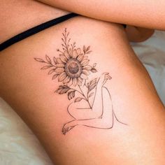 a woman with a sunflower tattoo on her thigh is laying down and looking at the camera