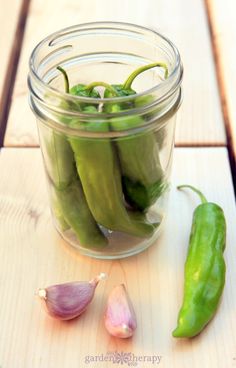 green peppers and garlic in a jar on a table