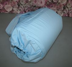 a baby blue blanket laying on top of a table next to a flowered wall